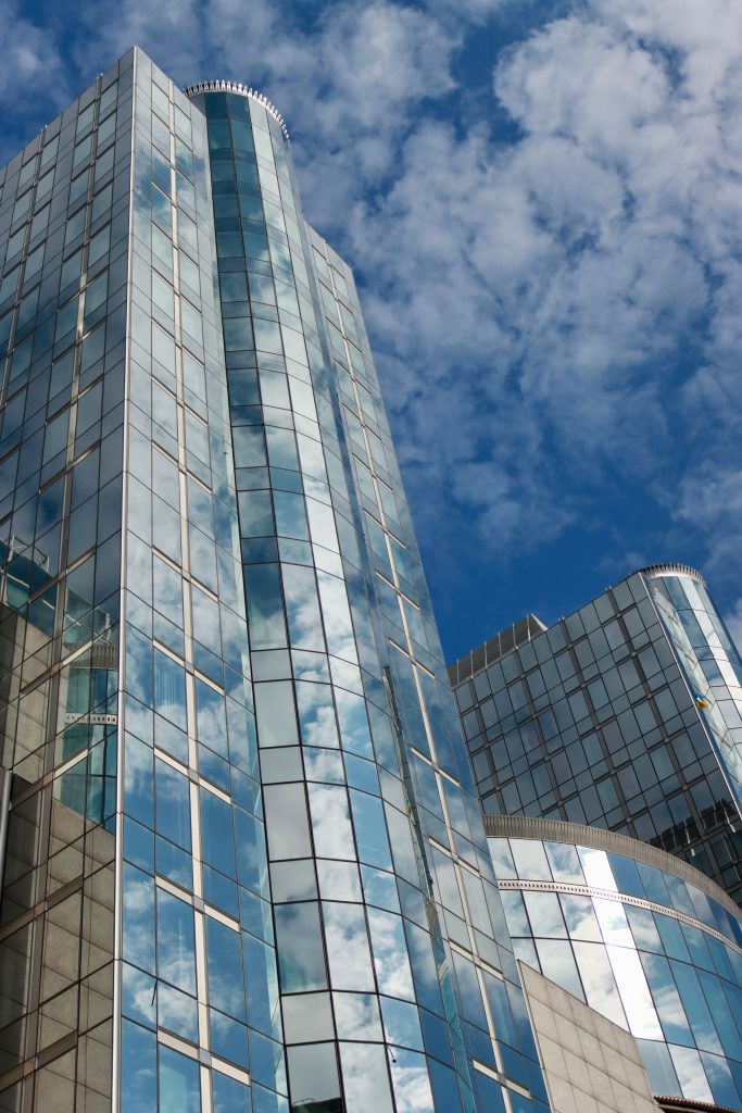 Low angle view of modern glass skyscrapers in Brussels reflecting clouds in a blue sky.